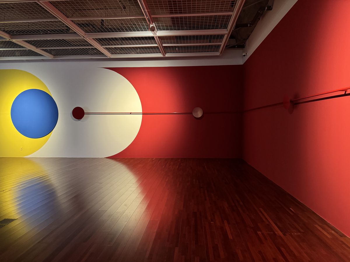 정소영, <We Predict into Existence>, 2025, 월페인팅, 조명, 스위치, 스테인리스 스틸 판, 파이프, 가변 크기. 인간은 고채도의 원색을 동시에 볼 때 시각적으로 부하와 혼란을 느끼기 쉽다. 작가는 인식의 혼란을 틈타 불예측성과 예외성을 보여주고자 빨강, 파랑, 노랑 3원색을 사용했다. 사진: 고영진