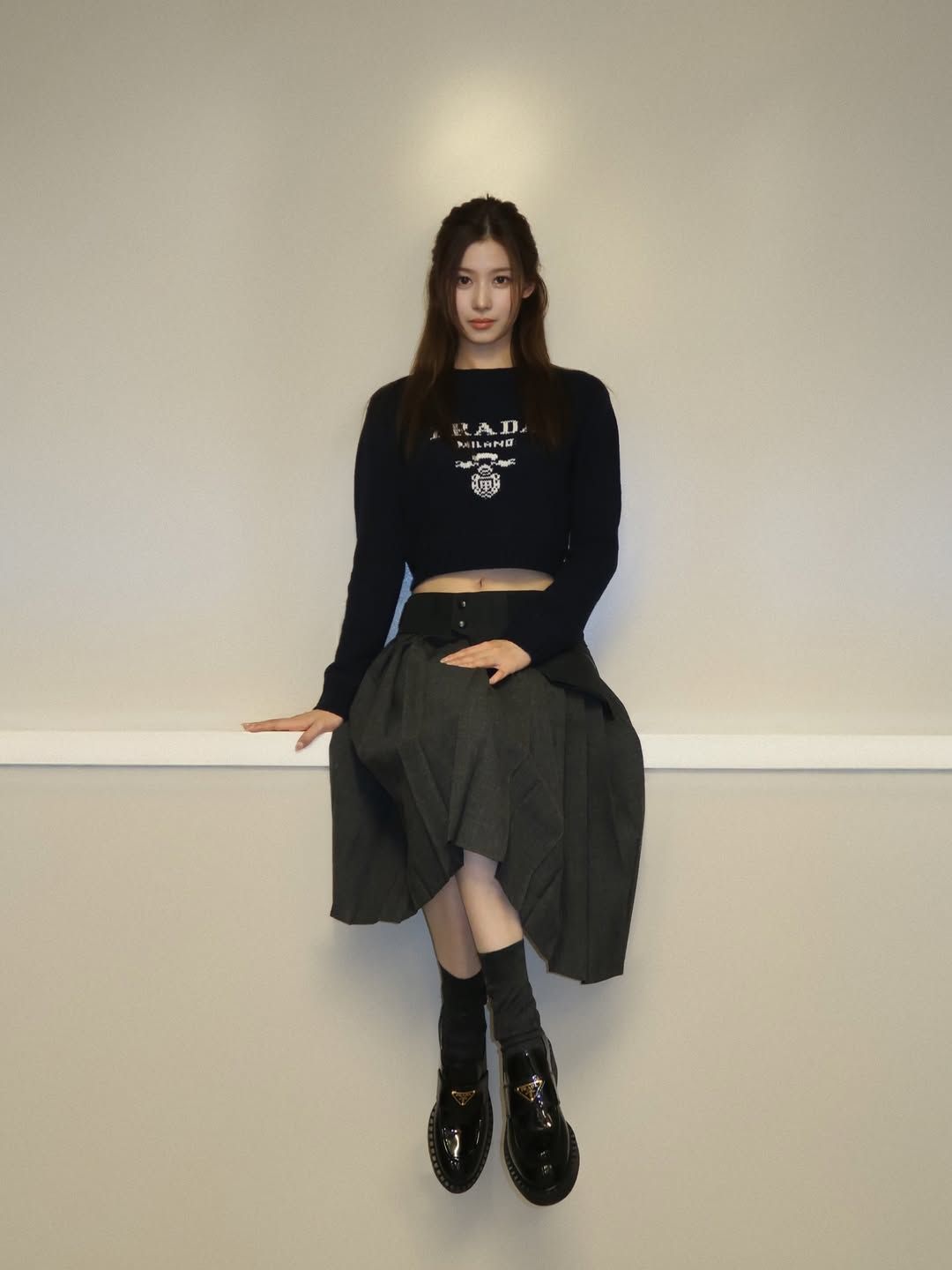 그레이 플리츠 롱 스커트와 블랙 프라다 로퍼를 착용해 고급스러운 겨울 룩을 완성한 사나 / @m.by__sana