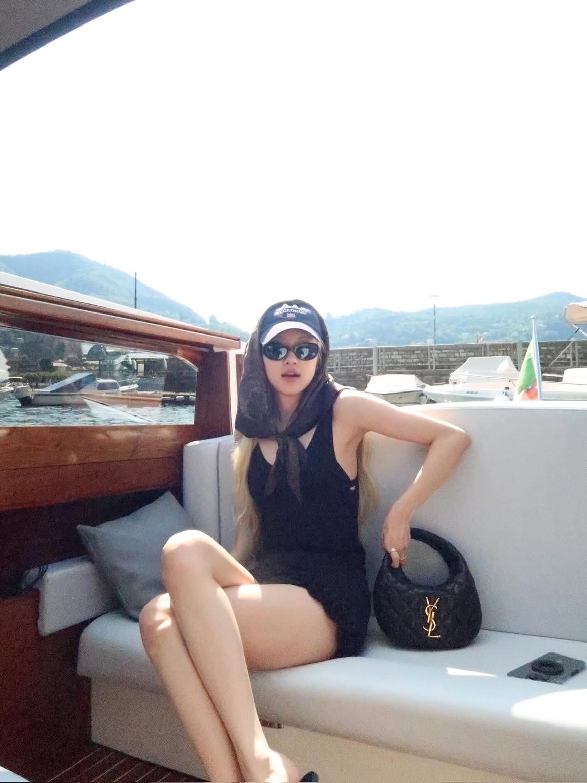 블랙 원피스에 볼캡과 헤드 스카프를 매치한 로제의 요트 룩.