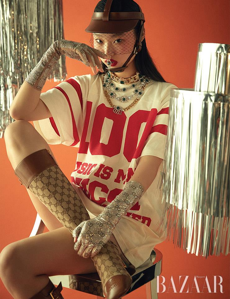 티셔츠, 헤드 기어 바이저, 코 피어싱, 레이어드한 4개의 목걸이, 크리스털 장갑, 롱 부츠는 모두 Gucci.