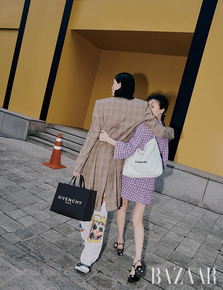 진영이 입은 코트는 가격 미정, 프린팅 팬츠는 3백64만원대, 토트백은 1백53만원 모두 Givenchy. 스니커즈는 Hermès. 루루가 입은 트위드 재킷, 스커트, 귀고리, 목걸이, ‘샤넬 22’ 백, 샌들 힐은 모두 Chanel.