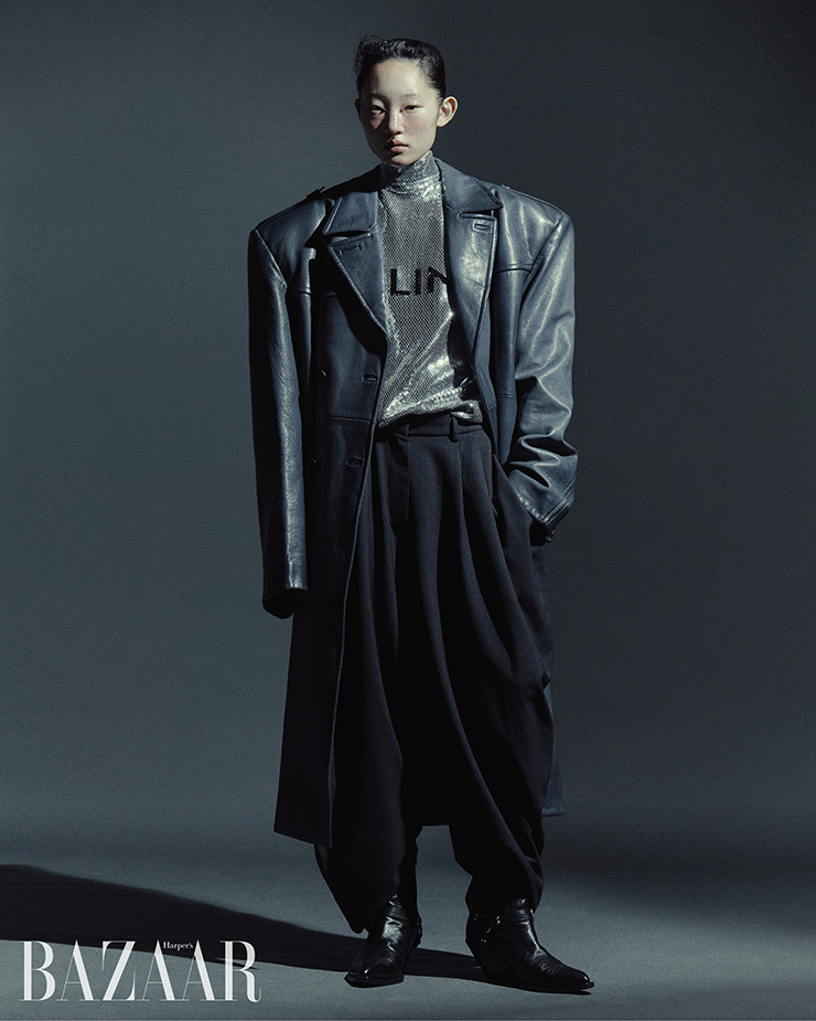 오버사이즈 가죽 코트는 Prada. 시퀸 톱, 앵클부츠는 Celine Homme by Hedi Slimane. 드레이프 팬츠는 Loewe.