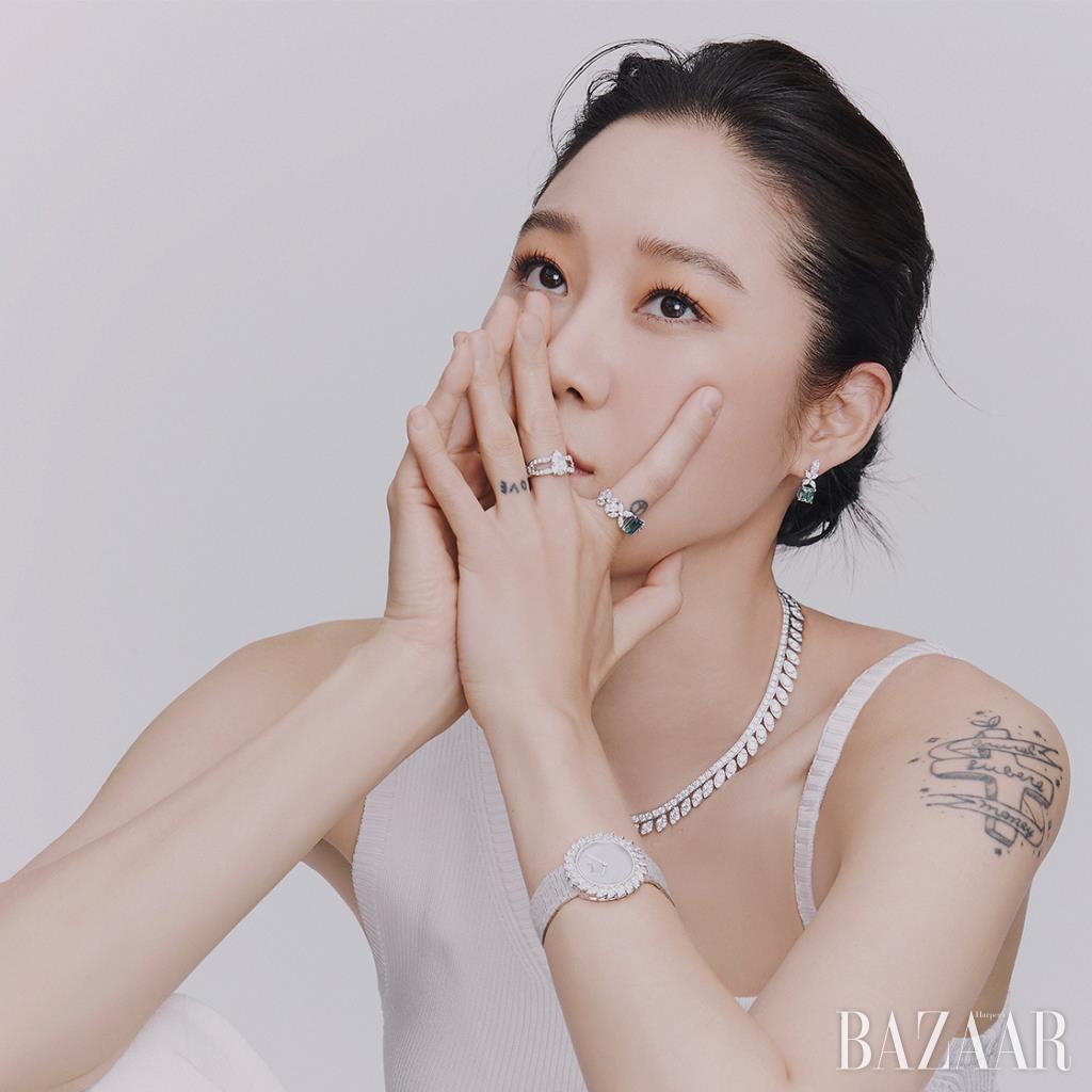 중지에 착용한 다이아몬드가 세팅된 플래티넘 소재의 ‘피아제 자댕 시크릿 인게이지먼트 링’, 검지와 귓불에 착용한 18K 화이트 골드에 에메랄드와 다이아몬드가 세팅된 ‘피아제 트레져 링’, ‘피아제 트레져 이어링’, 3백25개의 브릴리언트 컷 다이아몬드가 돋보이는 ‘라임라이트 익스트림리 피아제 네크리스’, 마르키즈 컷 다이아몬드와 화이트 마더오브펄 다이얼로 장식된 ‘윈터 썬 워치’는 모두 Piaget. 슬리브리스 톱은 Peter Do by 10 Corso Como. 팬츠는 Jacquemus by Mue.