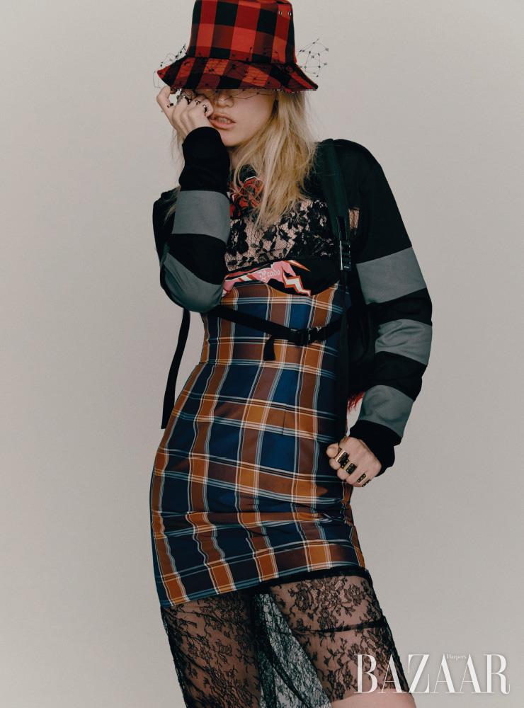  드레스는 3백31만원, 레이스 브라는 가격 미정, 백팩은 2백21만원 모두 Prada. 레이어드한 체크 스커트는 54만8천원 Push Button. 니트 발라클라바는 54만원 4 Moncler Simone Rocha. 버킷 모자는 Dior. 양손에 착용한 반지들은 모두 Louis Vuitton.