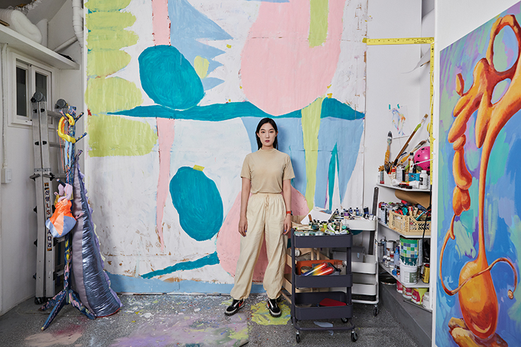 송은에서 9월 24일까지 열리는 그룹전 «Summer Love 2022»에서 새롭게 선보이는 평면작업 시리즈의 에스키스를 배경으로 포즈를 취한 우한나 작가.