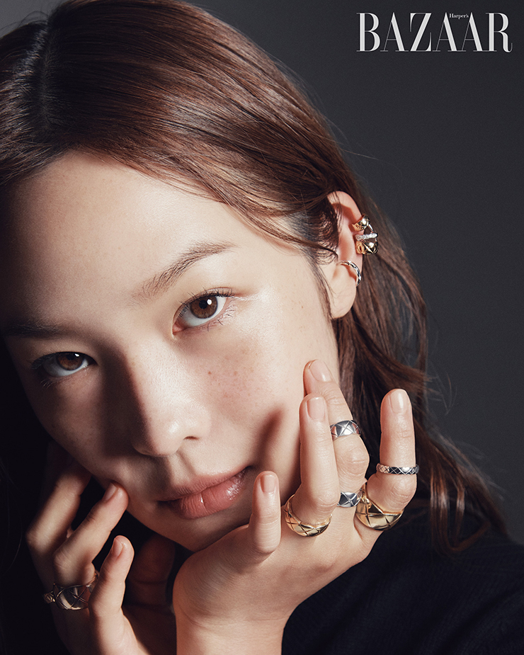 다이아몬드와 화이트 골드 그리고 옐로 골드가 조화로운 이어링, 화이트 골드에 다이아몬드를 장식한 이어링, 오른손 검지와 중지에 착용한 다이아몬드 장식의 화이트 골드와 옐로 골드가 조화로운 링, 약지에 착용한 베이지 골드 라지 링, 왼손 검지에 착용한 화이트 골드 미니 링, 옐로 골드 라지 링, 중지에 레이어드한 2개의 화이트 골드 스몰 링, 약지에 착용한 옐로 골드 스몰 링은 모두 Chanel Coco Crush. 카디건은 Chanel.