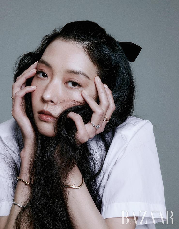 오른손에 착용한 핑크 골드와 다이아몬드 장식의 ‘브아 드 로즈’ 더블 반지, 두 개의 ‘브아 드 로즈’ 팔찌, 왼손 검지에 낀 핑크 골드와 다이아몬드 장식의 ‘브아 드 로즈’ 반지, 약지에 낀 화이트 골드와 다이아몬드 소재의 ‘로즈 디올 쿠튀르’ 반지, 옐로 골드에 다이아몬드가 장식된 ‘브아 드 로즈’ 팔찌는 모두 Dior Joaillerie. 셔츠는 Dior.