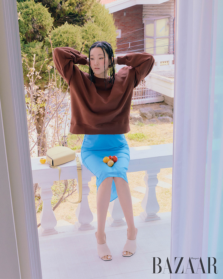 ‘엘리베이트 스퀘어드 50’ 샌들 힐,난간에 놓인 ‘텍스처블록 새들’ 백은 Ecco. 스커트는 Cos. 스웨트셔츠는 스타일리스트 소장품.