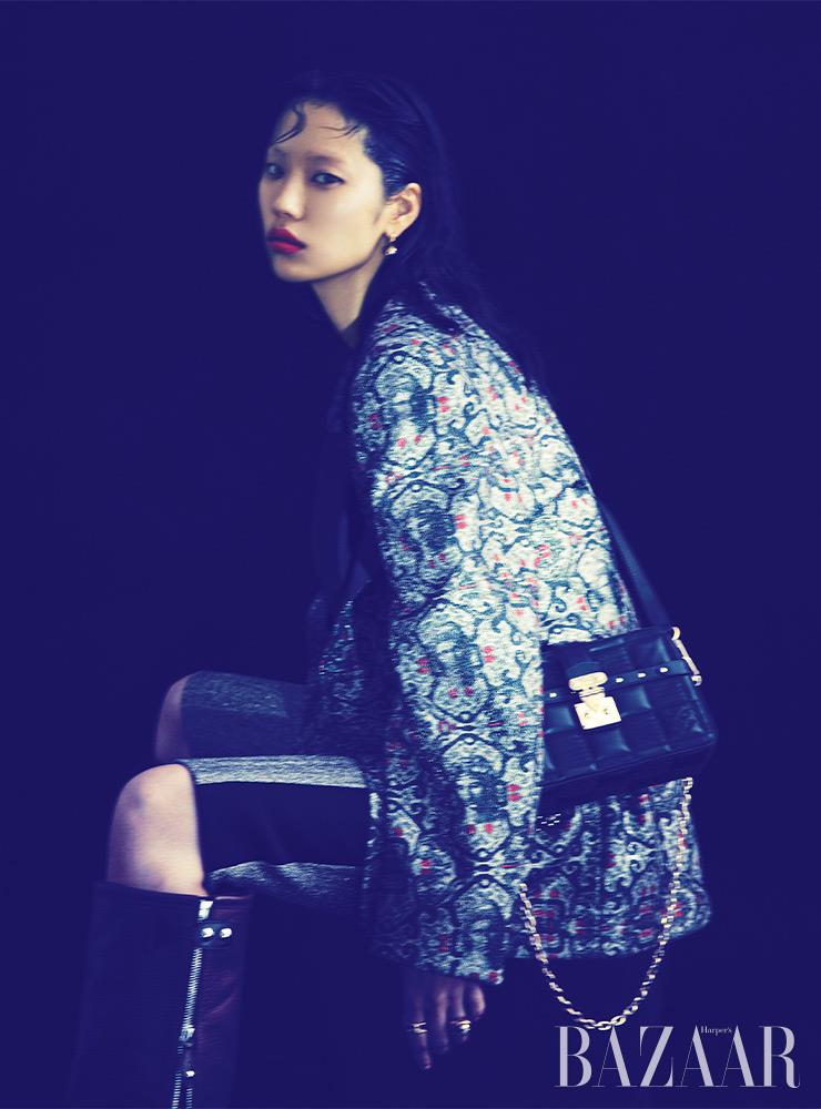 자카드 패턴 재킷, 카프리 팬츠, ‘B 블로썸’ 귀고리, 검지에 착용한 ‘LV 볼트’ 원 밴드 반지, 약지에 착용한 ‘B 블로썸’ 반지, ‘트로카’ 크로스 백, 롱 부츠는 모두 Louis Vuitton.