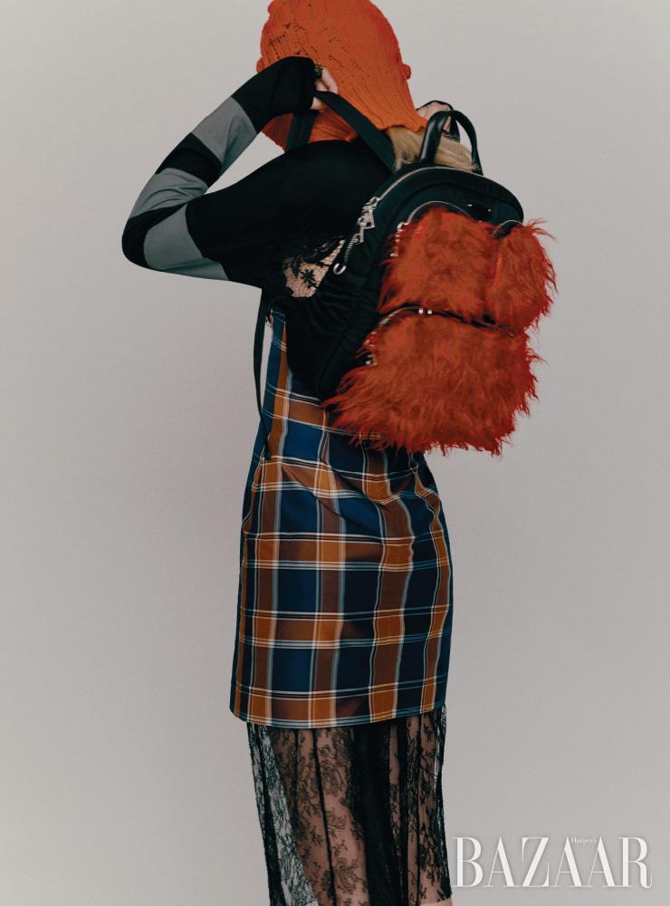  드레스는 3백31만원, 레이스 브라는 가격 미정, 백팩은 2백21만원 모두 Prada. 레이어드한 체크 스커트는 54만8천원 Push Button. 니트 발라클라바는 54만원 4 Moncler Simone Rocha. 버킷 모자는 Dior. 양손에 착용한 반지들은 모두 Louis Vuitton.