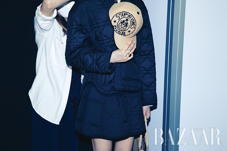 한 손에는 모자를, 다른 손에는 가방을 들고 스태프의 손길에 몸을 맡기고 있는 모델. 