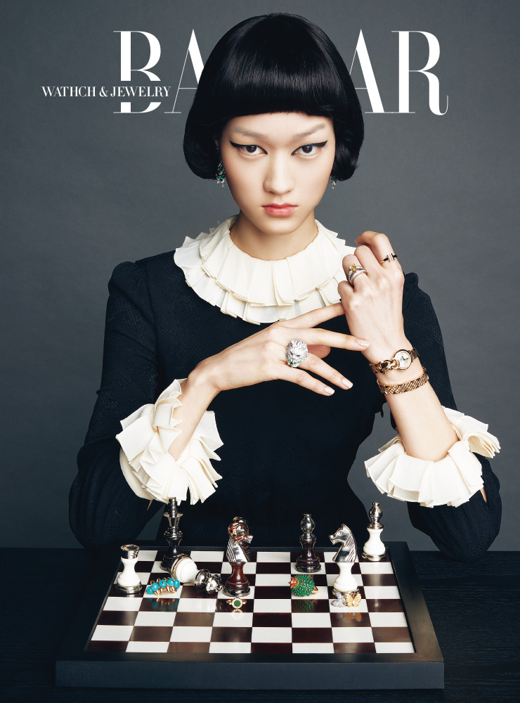 에메랄드 세팅 귀고리는 Chopard. 오른손에 착용한 ‘부 두26’ 컬렉션 블라디미르II 반지는 Boucheron. 왼손 검지에 착용한 ‘티파니 티 컬러’ 스퀘어 반지는 Tiffany & Co.. 약지에 착용한 ‘조세핀 오브 프랭타니에르’ 컬렉션 반지는 Chaumet. ‘팬더 드 까르띠에’ 컬렉션 더블 투어 시계는 Cartier. (체스판 왼쪽부터) ‘클래쉬 드 까르띠에’ 컬렉션의 싱글 귀고리는 Cartier. 체스 말에 걸린 뱀 모티프의 ‘에덴’ 컬렉션 반지는 Damiani. ‘불가리 불가리 클래식’ 컬렉션 반지는 Bvlgari. 선인장 모티프의 ‘칵투스 드 까르띠에’ 컬렉션 반지는 Cartier. ‘투 버터 플라이’ 컬렉션 귀고리는 Van Cleef & Arpels. 드레스는 Celine. 체스는 Design Mayo.
