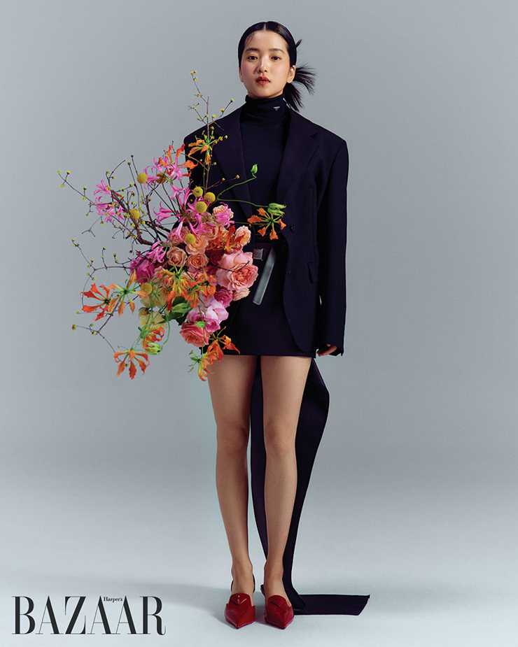 재킷, 하이넥 톱, 스커트, 슬링백 힐은 모두 Prada.