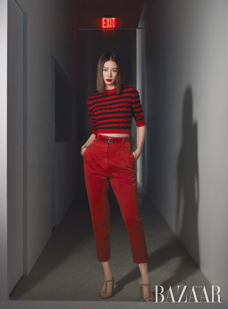캐시미어 소재 크롭트 풀오버, 레드 데님 팬츠, 팔찌, 카프 스킨 소재의 벨트, 주얼 장식 스웨이드 소재 샌들은 모두 Chanel.