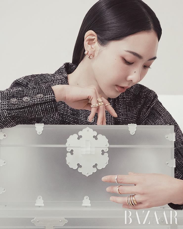 베이지 골드에 다이아몬드가 세팅된 이어링, 오른손 검지에 착용한 다이아몬드 장식의 옐로 골드 미니 링, 옐로 골드 스몰 링, 약지에 착용한 옐로 골드 스몰 링, 베이지 골드에 다이아몬드가 세팅된 라지 링, 소지에 착용한 베이지 골드 다이아몬드 스몰 링, 왼손 검지에 착용한 화이트 골드 미니 링, 중지에 착용한 베이지 골드 스몰 링, 약지에 착용한 옐로 골드와 화이트 골드에 다이아몬드를 장식한 링은 모두 Chanel CoCo Crush. 트위드 재킷은 Chanel.