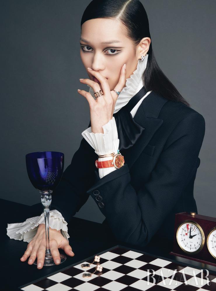 ‘팬더 드 까르띠에’ 귀고리는 Cartier. 검지에 착용한 ‘티파니 티 컬러’ 스퀘어 반지는 Tiffany & Co.. 약지에 착용한 ‘비제로원 락’ 반지는 Bvlgari. 각각 터쿼이즈, 말라카이트가 세팅된 ‘포제션’ 컬렉션 뱅글은 Piaget. 고흐의 작품에서 영감을 받아 완성한 ‘에크리뛰르 드 쇼메’ 컬렉션 시계는 Chaumet. 체스판 위의 ‘매직 알함브라’ 컬렉션 귀고리는 Van Cleef & Arpels. 재킷은 Dior. 보타이 장식 셔츠는 Ralph Lauren Collection. 와인잔은 Hermès. 체스는 Design Mayo.