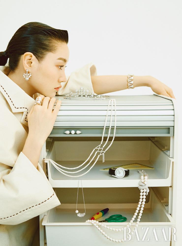 모델이 착용한 물방울 모티프의 ‘조세핀 아그레뜨 임페리얼’ 귀고리는 4천만원대 Chaumet. 오른손의 번개 모티프의 ‘레이디 스타더스트 펄’ 반지는 Stephen Webster. 왼팔의 다이아몬드와 마더오브펄이 세팅된 팔찌는 7천8백만원대 Bvlgari. (위부터) 서랍장에 세팅된 ‘조세핀 아그레뜨 임페리얼 디아뎀’ 티아라는 1억원대 Chaumet. 코르셋을 연상케하는 목걸이는 Tasaki. 다이아몬드와 남양 진주가 장식된 바 브로치는 Addir. 마더오브펄 다이얼로 세팅된 ‘라임라이트 갈라’ 시계는 Piaget. 리본 모양 다이아몬드와 아코야 진주로 장식한 목걸이는 Addir. 깃털 모티프에 핑크 크림 진주가 더해진 목걸이는 Chanel Fine Jewerly. 재킷은 Miu Miu.