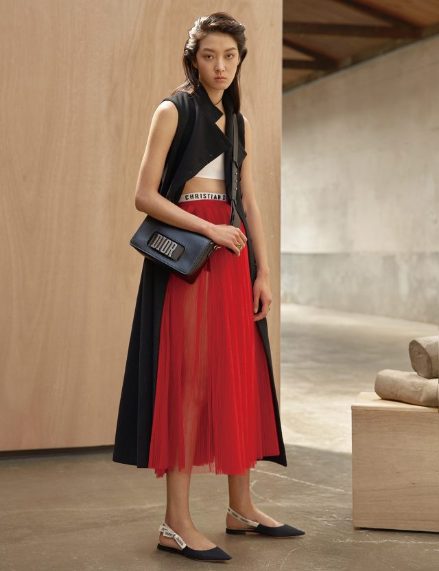 슬리브리스 롱 코트, 스포티한 무드의 브라 톱, 시스루 플리츠 스커트, 로고 밴드가 돋보이는 쇼츠, 초커, 반지, ‘DIOR’ 로고가 특징인 백, 리본 스트랩이 가미된 키튼 힐은 모두 Dior 제품.
