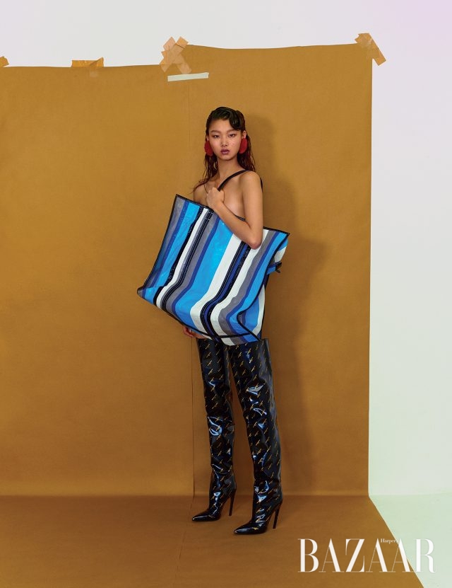 스트라이프 패턴의 오버사이즈 ‘바자’ 백, 로고 사이하이 부츠, 화보에서 계속 착용하고 있는 퍼 귀고리는 모두 Balenciaga 제품.