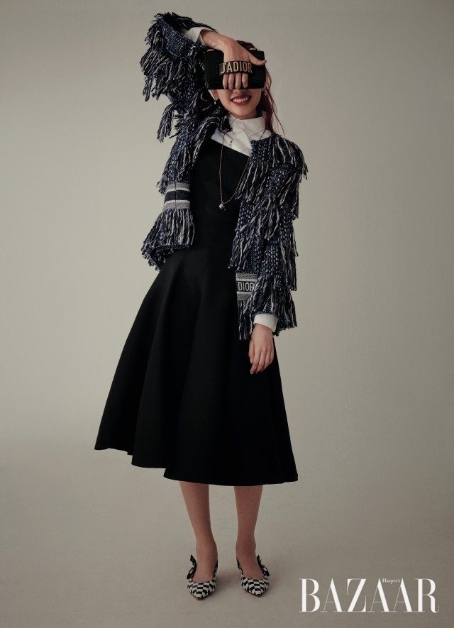 프린지 디테일의 트위드 재킷, 화이트 셔츠, 원피스, 귀고리, 목걸이, 로고 장식의 클러치 겸용 숄더백, 체커보드 패턴의 슬링백 슈즈는 모두 Dior 제품.