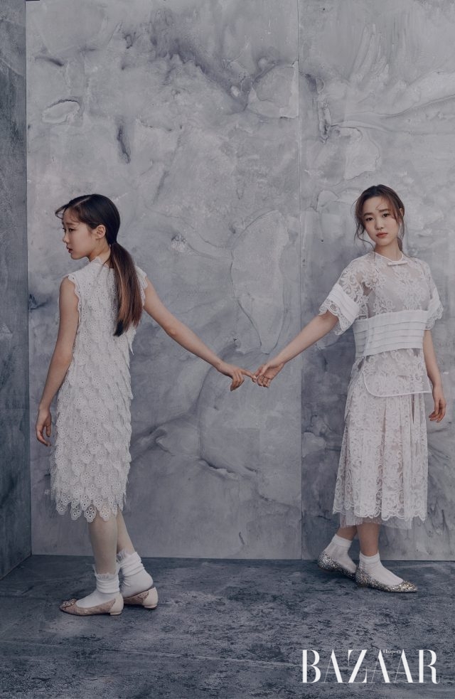 안소현이 입은 꽃잎 모티프 레이스 소재의 로맨틱한 드레스는 Chloé, 주얼이 장식된 레이스 플랫 슈즈는 Manolo Blahnik 제품. 박소연이 입은 리본과 핀턱 디테일의 레이스 블라우스, 스커트는 모두 N°21, 골드 글리터 플랫 슈즈는 Jimmy Choo 제품.