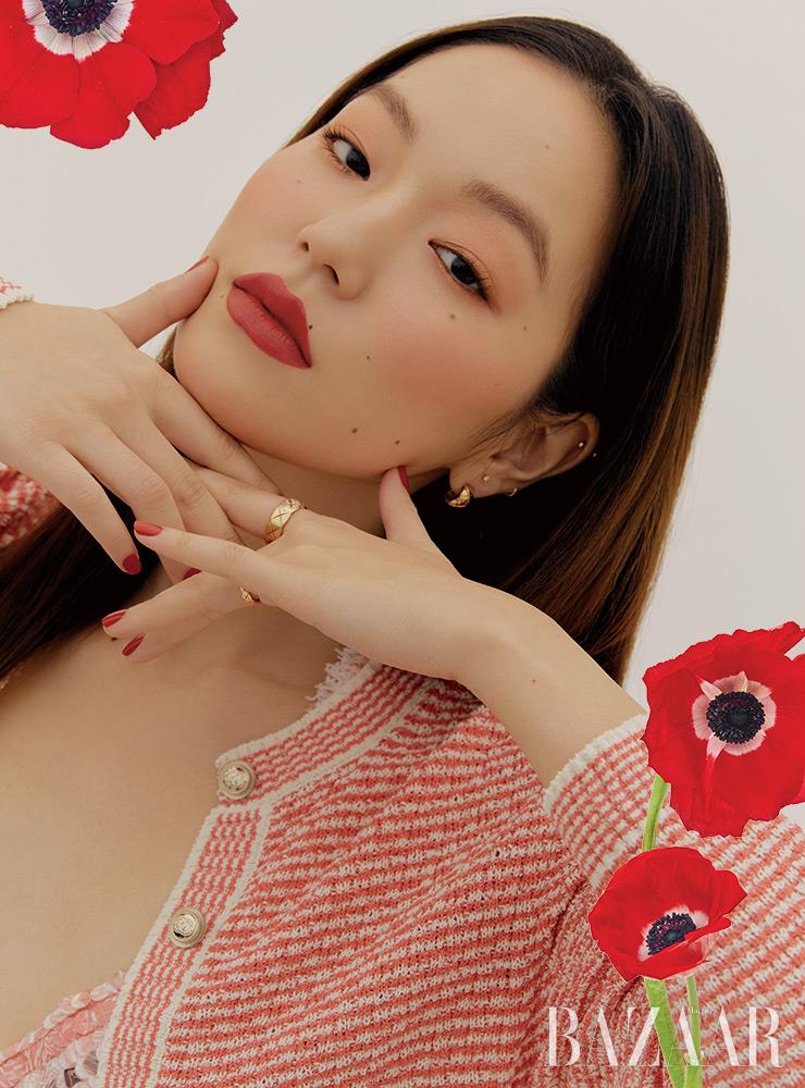 눈가를 물들인 샤넬 ‘레 꺄트르 옹브르’ 368 장미색과 입술 위 ‘루쥬 알뤼르 벨벳 엑스트렘 마뜨’ 136의 레드, 볼에 스민 ‘플뢰르 드 쁘렝땅’의 피치 컬러가 한데 모여 꽃이 만개한 정원을 거닌 듯 화사하고 향기롭다. 트위드 소재의 톱, 코튼과 폴리아미드 소재의 롱 카디건은 Chanel. 퀼팅 모티프의 옐로 골드 귀고리, 다이아몬드가 세팅된 골드 반지, 퀼팅 모티프의 옐로 골드 반지는 모두 Chanel Fine Jewelry.