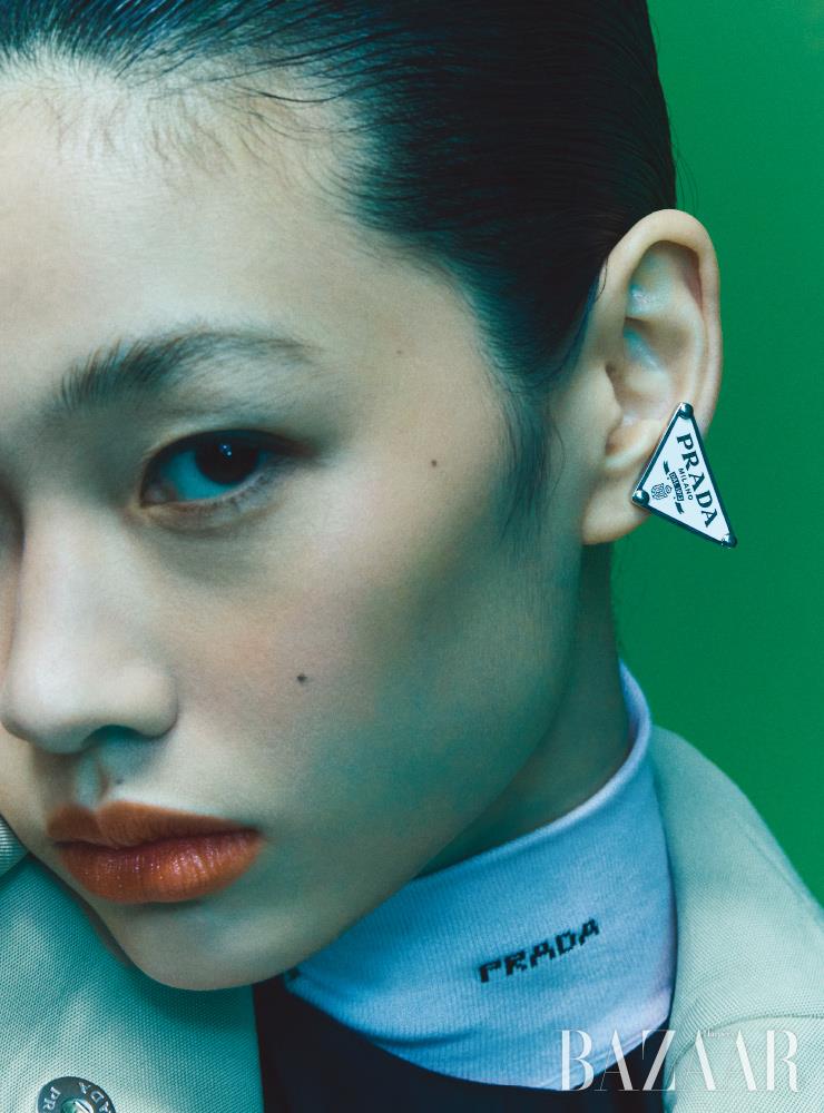 롱 코트, 리-나일론 드레스, 이너 톱, 로고 이어커프는 모두 Prada.
