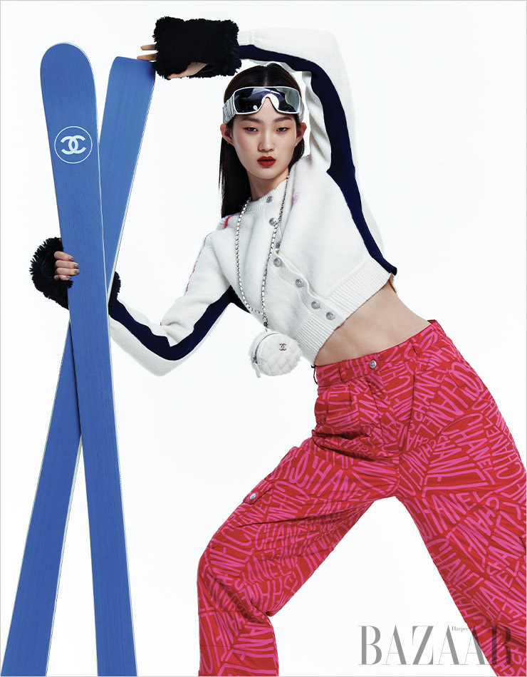 카디건, 팬츠, 고글, 시어링 소재의 체인 클러치, 글러브, 스키는 모두 Chanel.