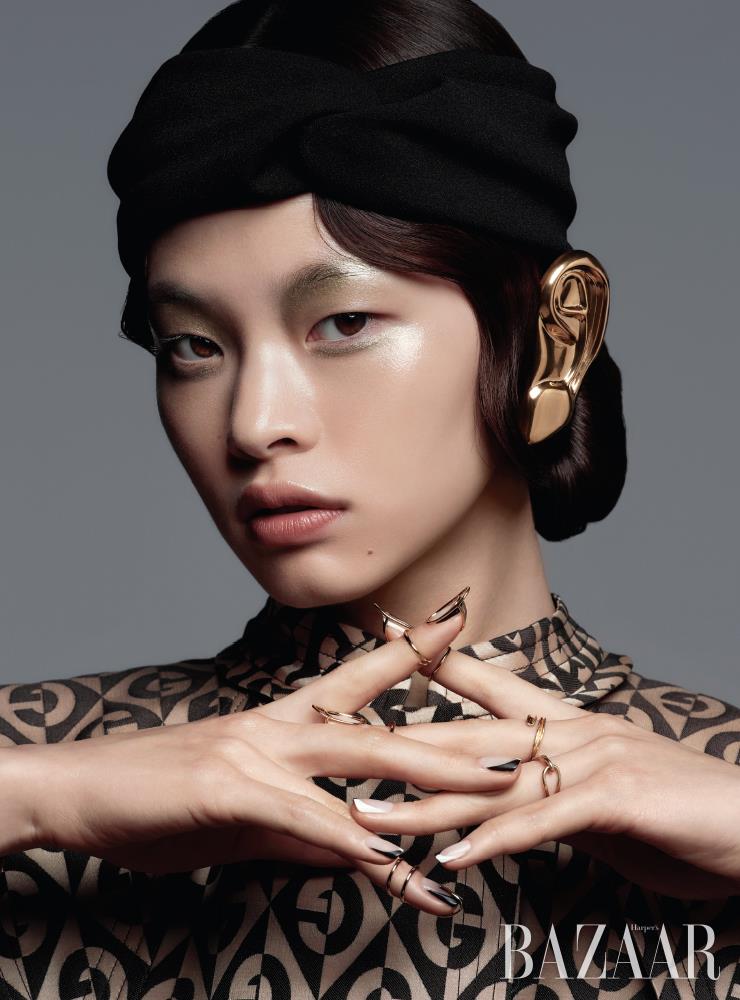귀를 덮는 액세서리, 로고 패턴 코트는 모두 Gucci. 네일 주얼리는 Unistella. 터번 헤어밴드는 스타일리스트 소장품. 