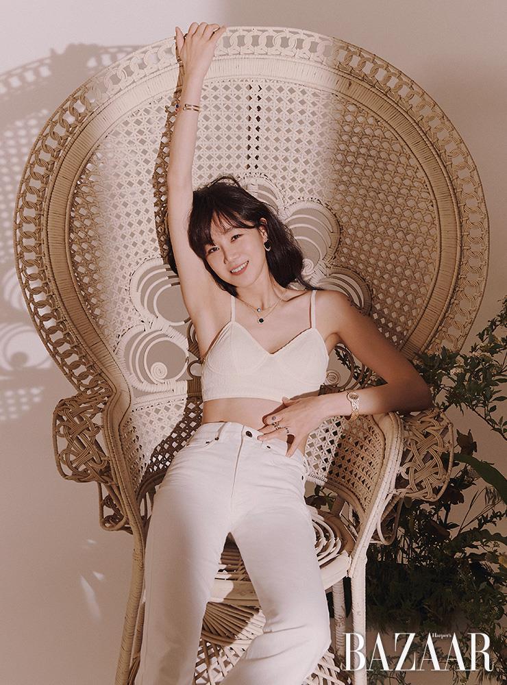 오른팔에 착용한 딥 블루 라피스라줄리 카보숑과 커넬리언 카보숑이 장식된 2개의 ‘포제션 오픈 뱅글 브레이슬릿’, ‘피아제 선라이트 이어링’, 18K 핑크 골드에 말라카이트와 다이아몬드가 세팅된 ‘피아제 선라이트 펜던트’, 블루 터쿼이즈 카보숑이 돋보이는 ‘포제션 체인 펜던트’, 은은한 광채가 돋보이는 ‘익스트림리 레이디 워치’, 선명한 말라카이트가 양쪽 끝에 장식된 ‘포제션 말라카이트 오픈 링’, 18K 핑크 골드 링에 다이아몬드가 장식된 ‘포제션 링’은 모두 Piaget. 브라톱은 Eenk. 팬츠는 Miu Miu.