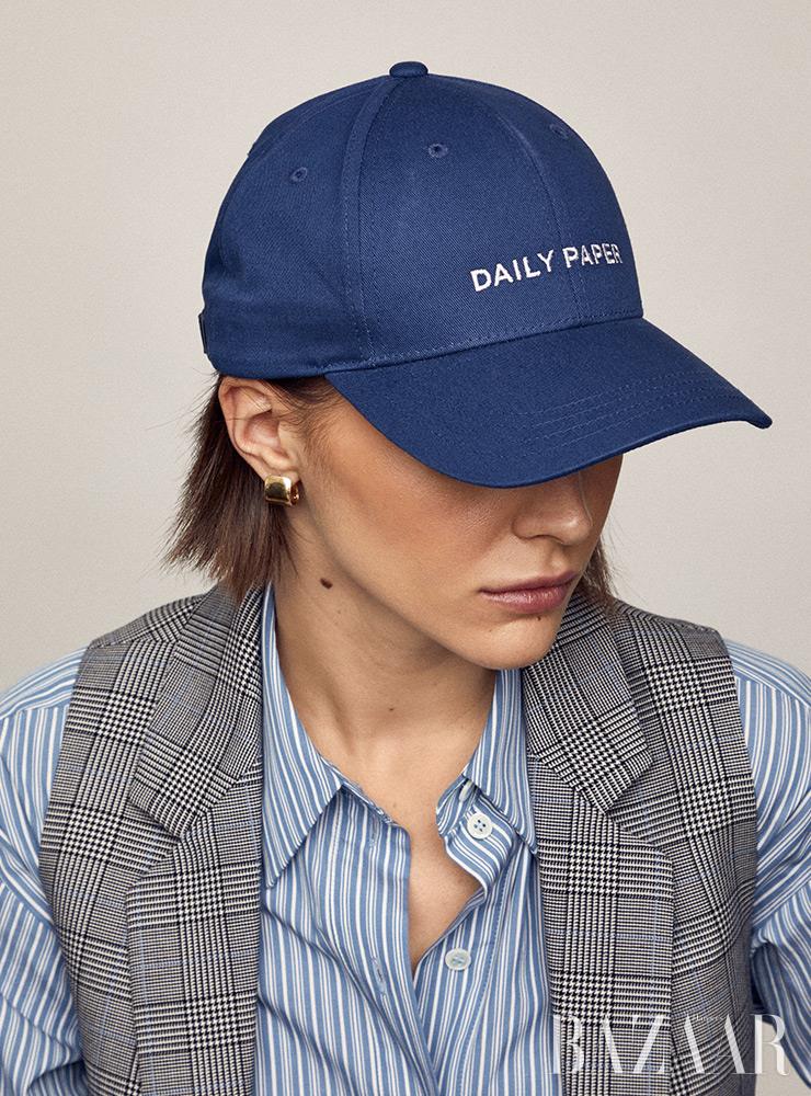 로고 캡 모자는 Daily Paper. 셔츠, 체크 베스트는 Michael Kors Collection. 귀고리는 Jennifer Fisher.