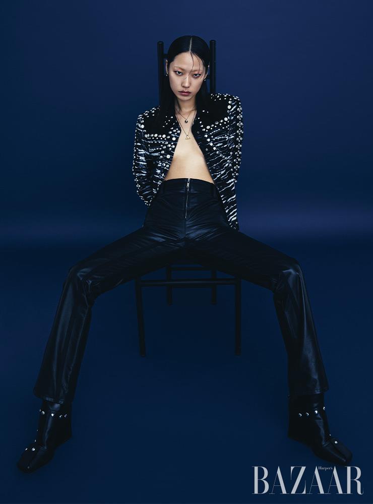 스터드 장식의 패턴 재킷, 레더 팬츠, ‘B 블로썸’ 귀고리, 목걸이, 로고 펜던트의 ‘LV 볼트’ 목걸이, 앵클부츠는 모두 Louis Vuitton.